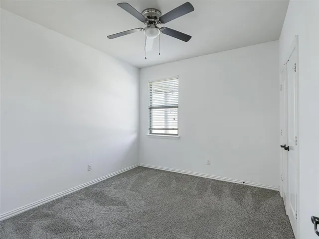 an empty room with a ceiling fan and window