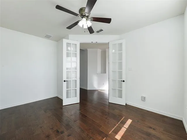 an empty room with wooden floor and a ceiling fan