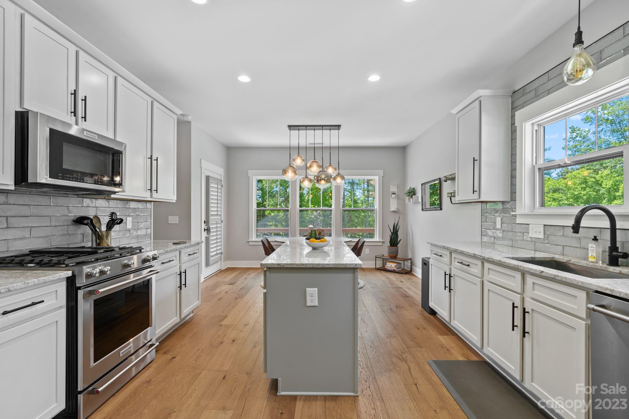 44 Reta Road Fairview, NC 28730 - Photo 13 of 36 a kitchen with stainless steel appliances granite countertop a stove top oven a sink dishwasher a dining table and chairs with wooden floor