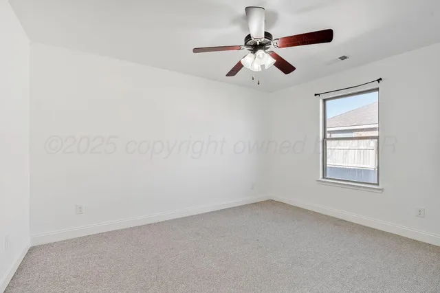 an empty room with a window and a fan