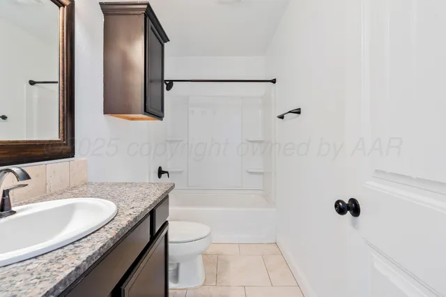 a bathroom with a granite countertop sink a toilet and shower