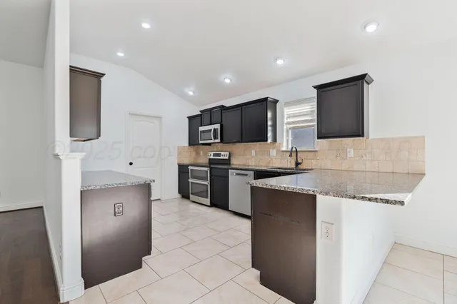 a kitchen with stainless steel appliances granite countertop a refrigerator a stove top oven a sink and dishwasher