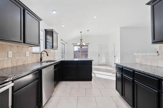 a large kitchen with granite countertop a sink and cabinets