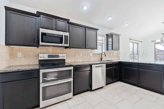 a kitchen with stainless steel appliances granite countertop a stove microwave and sink