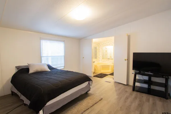 a bedroom with a bed and a flat tv screen on a dresser