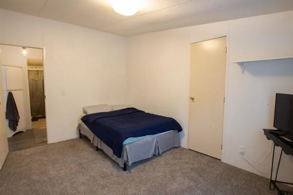 a room with a bed and a flat tv screen on a dresser