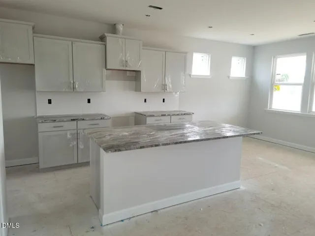a kitchen with granite countertop white cabinets and a sink