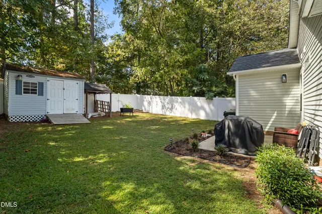 a view of a backyard with table and chairs potted plants and large tree