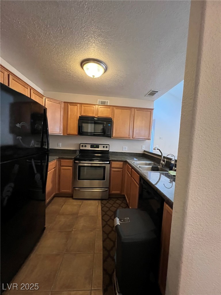 9325 West Desert Inn Road, Unit 206 Las Vegas, NV 89117 - Photo 15 of 37 Kitchen with black appliances, a textured ceiling, and brown cabinets