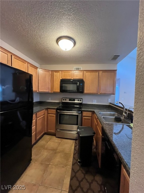 9325 West Desert Inn Road, Unit 206 Las Vegas, NV 89117 - Photo 23 of 37 Kitchen with black appliances, a textured ceiling, brown cabinetry, dark stone countertops, and light tile patterned flooring
