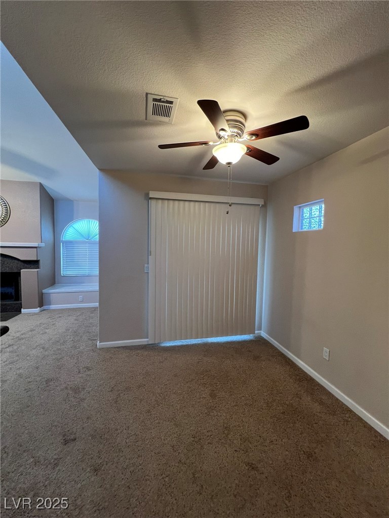 9325 West Desert Inn Road, Unit 206 Las Vegas, NV 89117 - Photo 24 of 37 Spare room featuring a textured ceiling, carpet, a fireplace, and ceiling fan