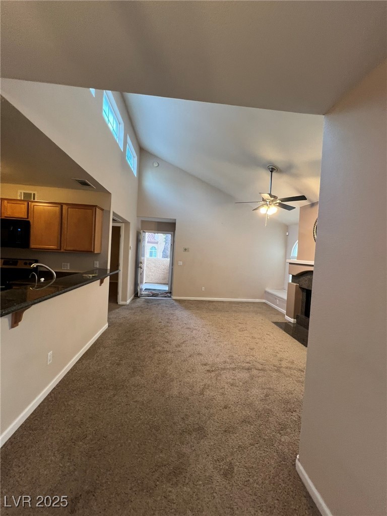 9325 West Desert Inn Road, Unit 206 Las Vegas, NV 89117 - Photo 29 of 37 Unfurnished living room with high vaulted ceiling, a fireplace with flush hearth, and carpet floors