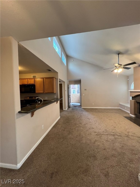 9325 West Desert Inn Road, Unit 206 Las Vegas, NV 89117 - Photo 30 of 37 Unfurnished living room with dark colored carpet, high vaulted ceiling, a fireplace with flush hearth, and ceiling fan