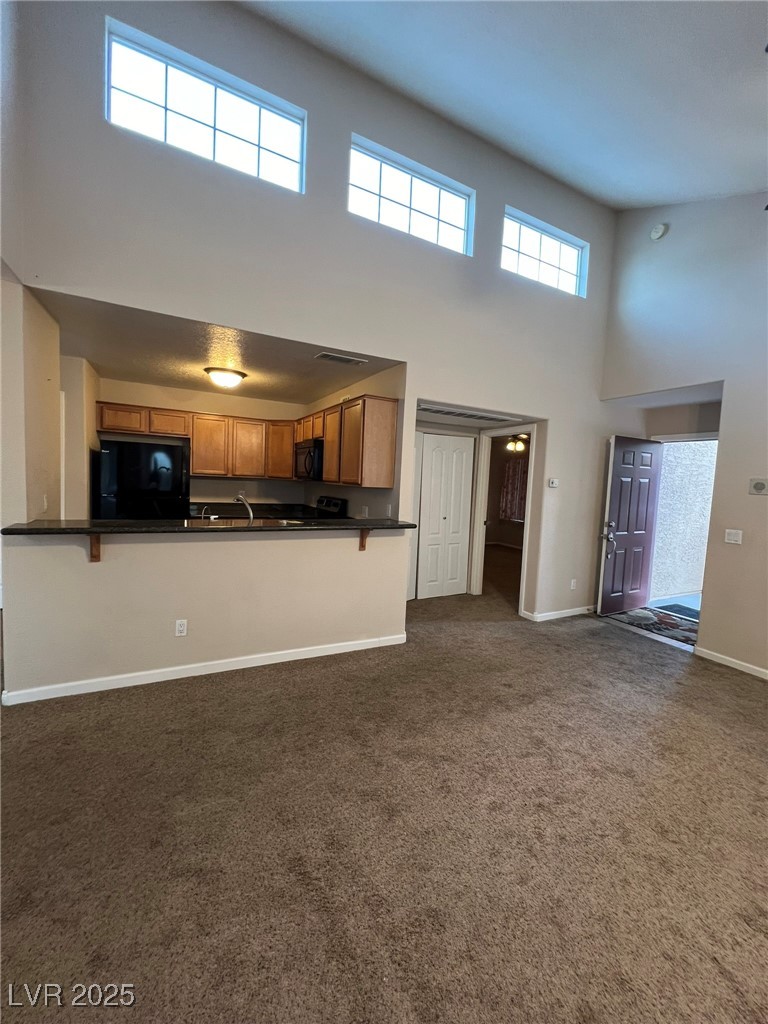 9325 West Desert Inn Road, Unit 206 Las Vegas, NV 89117 - Photo 33 of 37 Unfurnished living room with a high ceiling and dark colored carpet