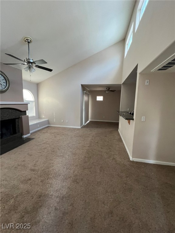 9325 West Desert Inn Road, Unit 206 Las Vegas, NV 89117 - Photo 4 of 37 Unfurnished living room featuring ceiling fan, a fireplace with flush hearth, high vaulted ceiling, and carpet flooring