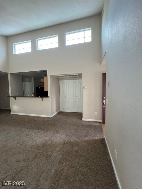 9325 West Desert Inn Road, Unit 206 Las Vegas, NV 89117 - Photo 5 of 37 Unfurnished living room featuring a high ceiling and dark carpet