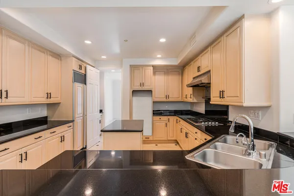 a kitchen with stainless steel appliances granite countertop a sink a stove and a refrigerator