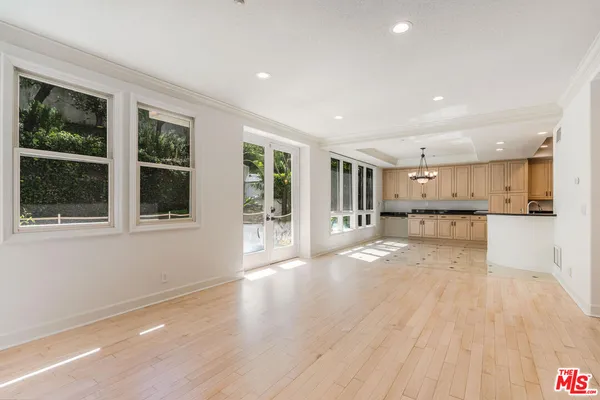 a view of an empty room with wooden floor and a kitchen