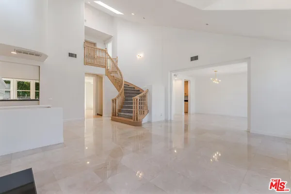 a view of an empty room with stairs and wooden floor