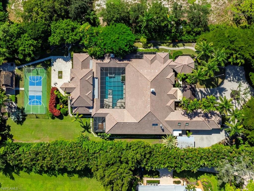 an aerial view of residential house with outdoor space and trees all around
