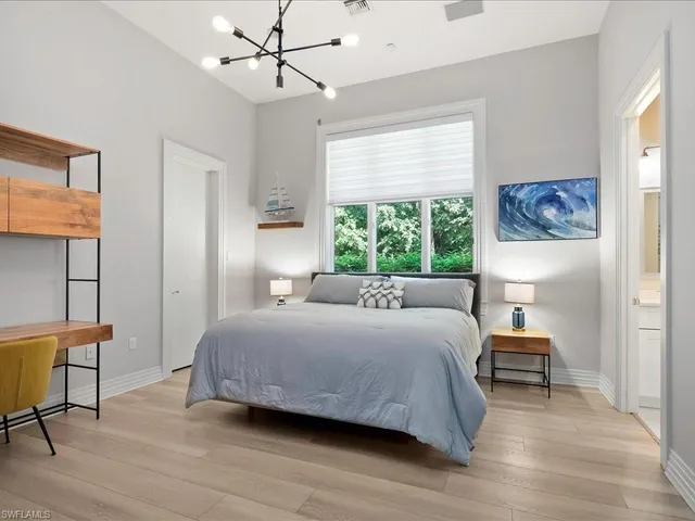 a bedroom with a bed a chair and a large window