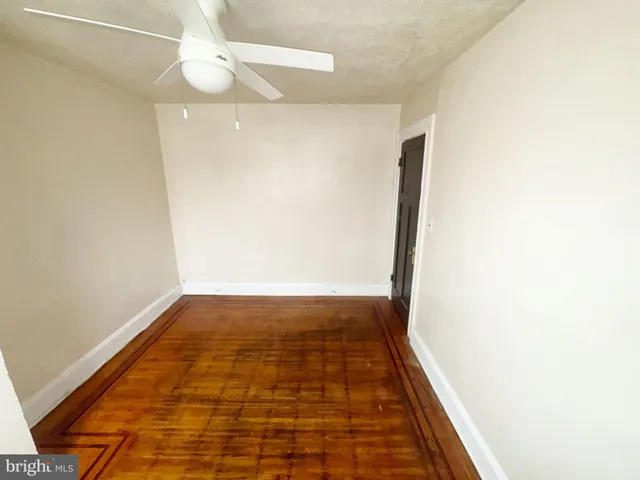 an empty room with wooden floor and fan