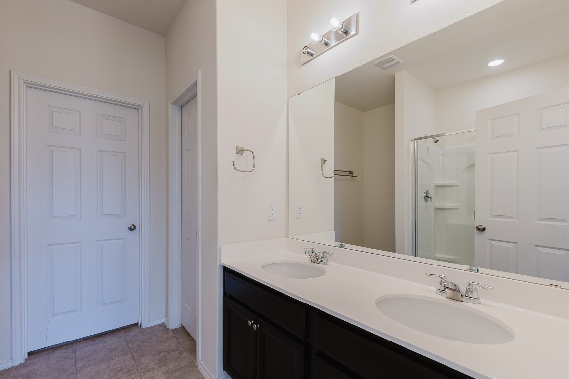 529 Gray Hawk Ridge Leander, TX 78641 - Photo 17 of 36 Bathroom with double vanity, tile patterned flooring, a shower, and recessed lighting