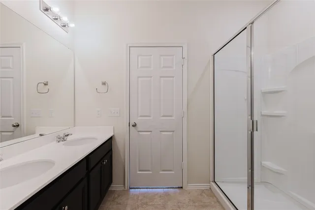 a bathroom with a double vanity sink a mirror and a shower