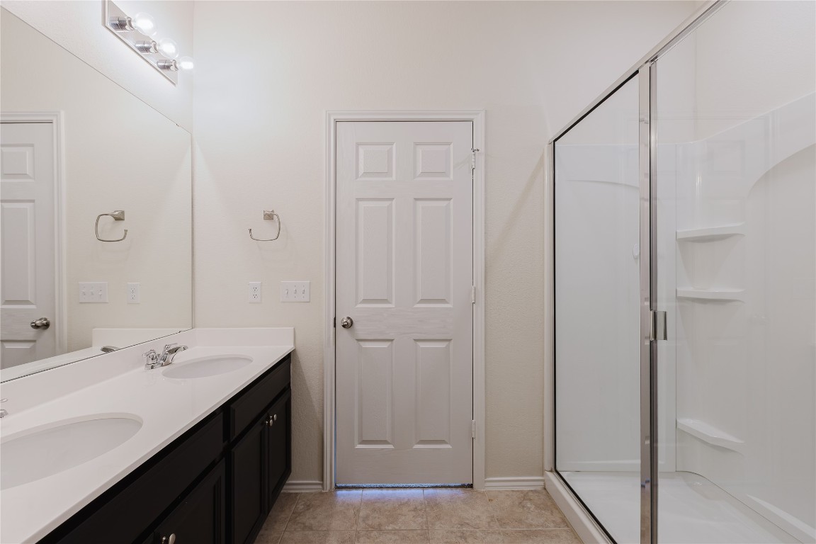 529 Gray Hawk Ridge Leander, TX 78641 - Photo 18 of 36 Full bath featuring double vanity, a shower stall, and tile patterned flooring