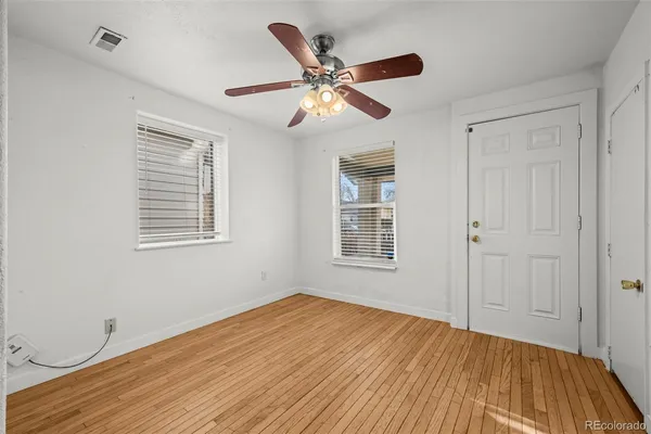 a view of empty room with wooden floor and fan