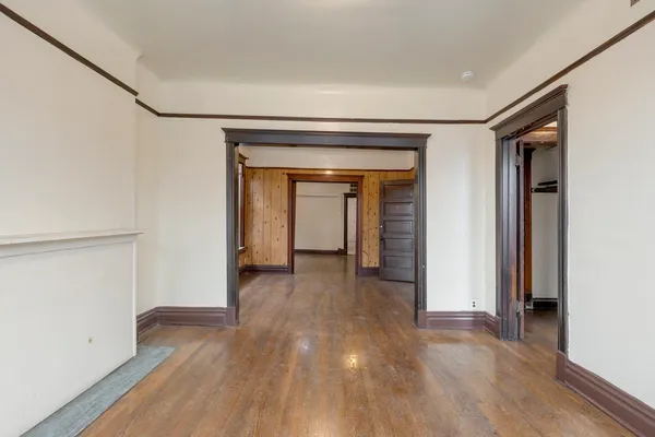 a view of an empty room with a window and hardwood floor