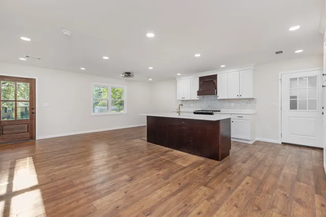 a kitchen with stainless steel appliances granite countertop a stove a sink and a refrigerator with wooden floor