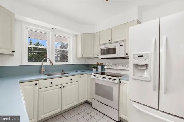 a kitchen with white cabinets and white appliances