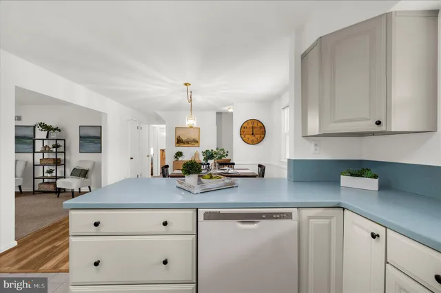 a open kitchen with granite countertop a sink white cabinets and chairs