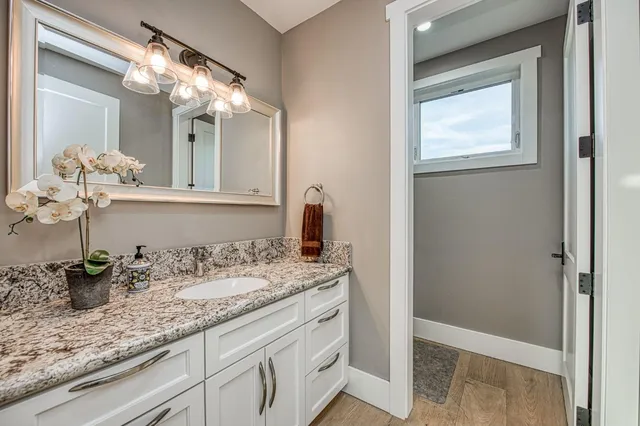 a bathroom with a granite countertop sink a large mirror and vanity