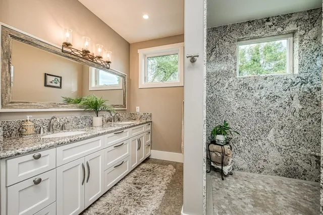 a spacious bathroom with a granite countertop sink a mirror and a shower