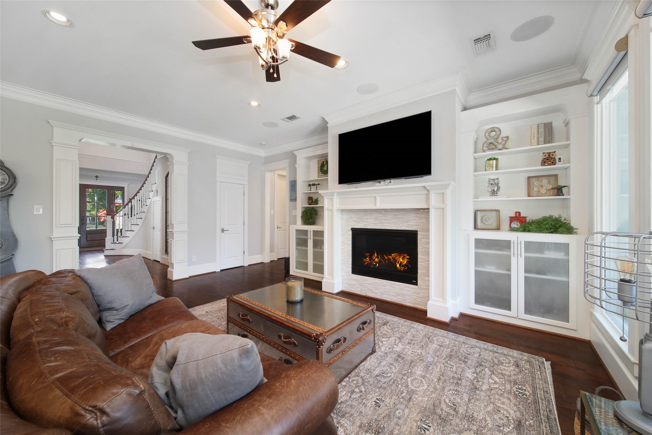 416 West 33rd Street Houston, TX 77018 - Photo 9 of 47 Sophisticated living room designed for both everyday comfort and elevated entertaining, featuring rich hardwood floors, extensive millwork, custom built-ins and a stunning fireplace accented by an elegant stacked stone surround. Oversized windows bathe the space in natural light while the open-concept layout creates a seamless flow throughout the home.