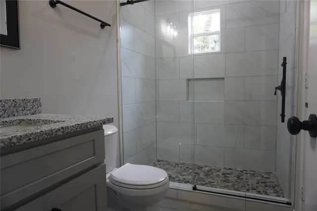 a bathroom with a granite countertop toilet a sink and a shower