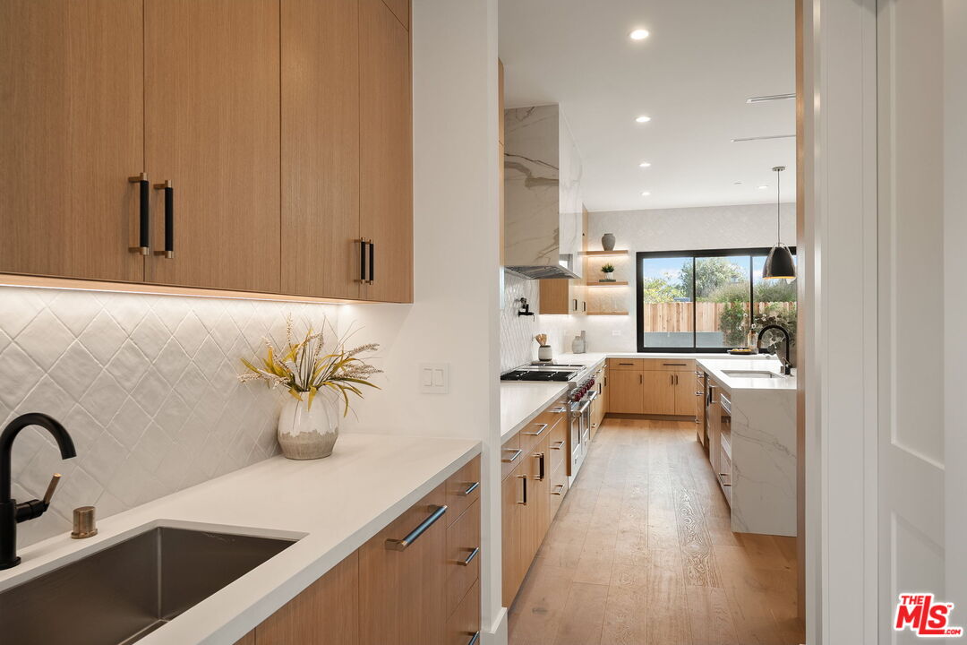 1742 Preuss Road Los Angeles, CA 90035 - Photo 12 of 50 a large white kitchen with sink a stove and a refrigerator with wooden floor