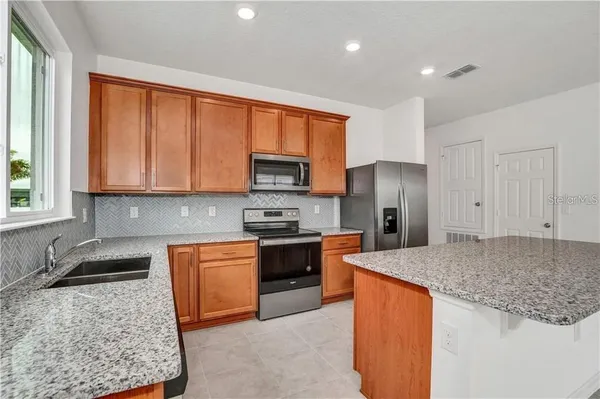 a kitchen with stainless steel appliances granite countertop a stove a sink dishwasher a refrigerator and a microwave oven