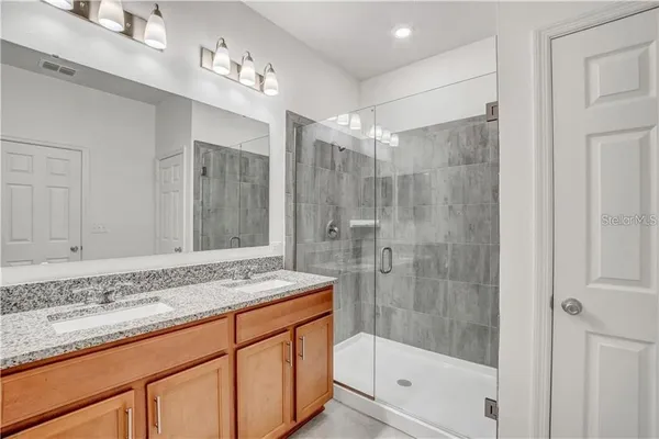 a bathroom with a granite countertop sink a mirror and shower