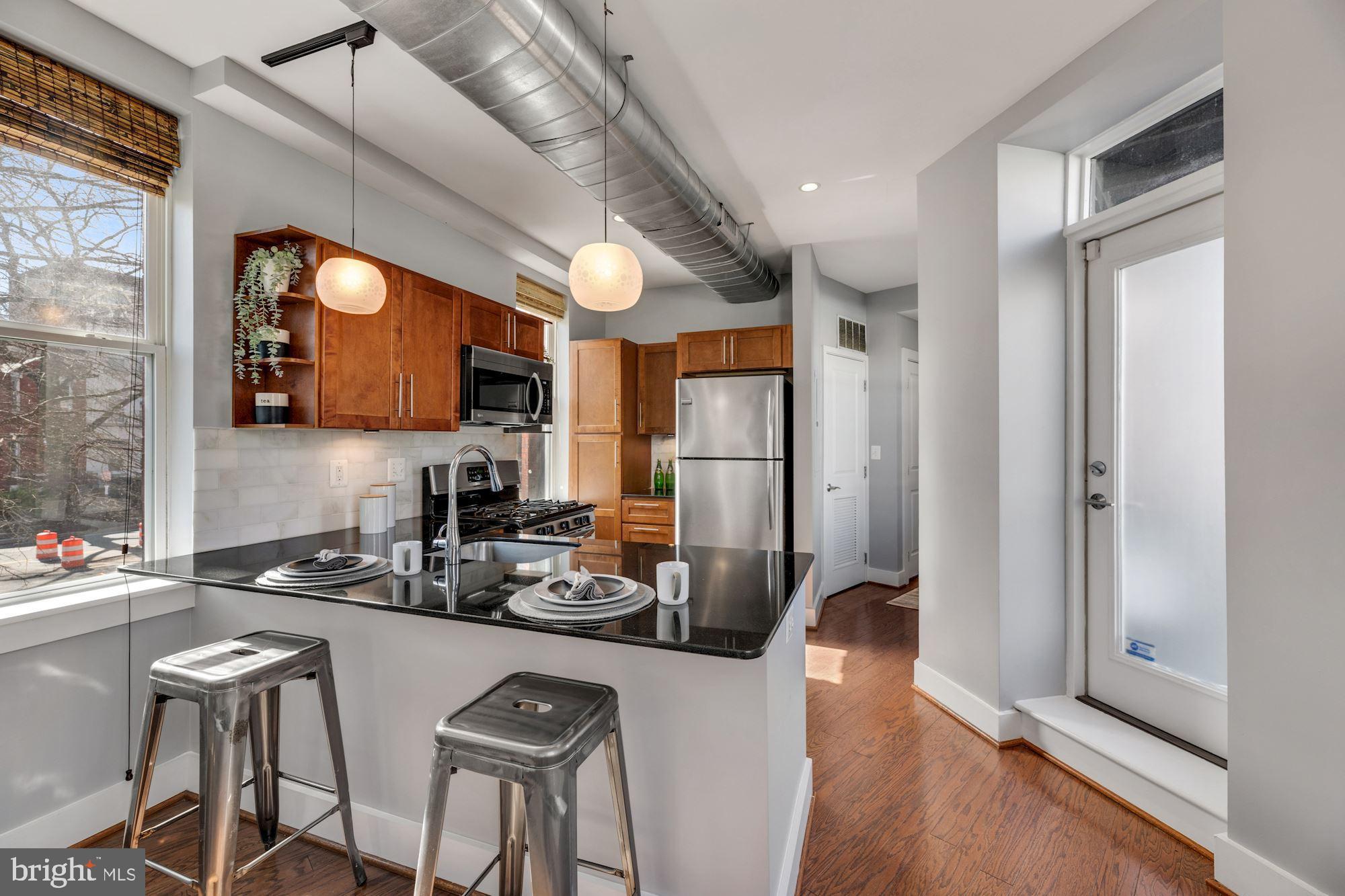 143 Rhode Island Avenue Northwest, Unit 3 Washington, DC 20001 - Photo 5 of 18 a kitchen with stainless steel appliances granite countertop a refrigerator a stove a sink a dining table and chairs with wooden floor