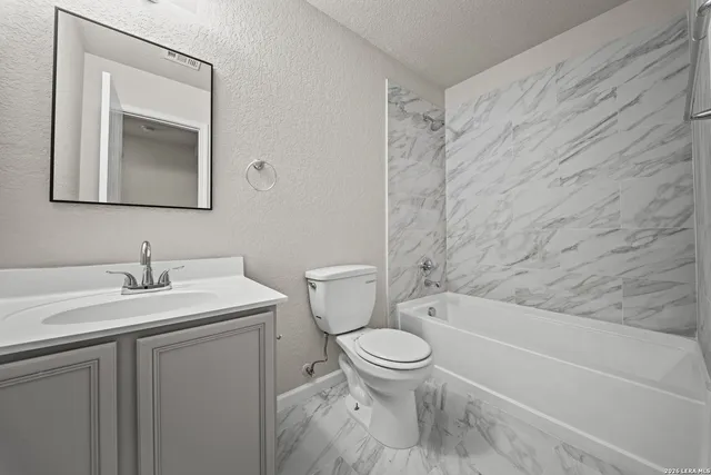 a bathroom with a toilet sink vanity tub and mirror