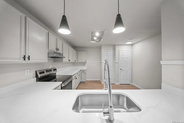 a kitchen with stainless steel appliances granite countertop a sink a stove and a refrigerator