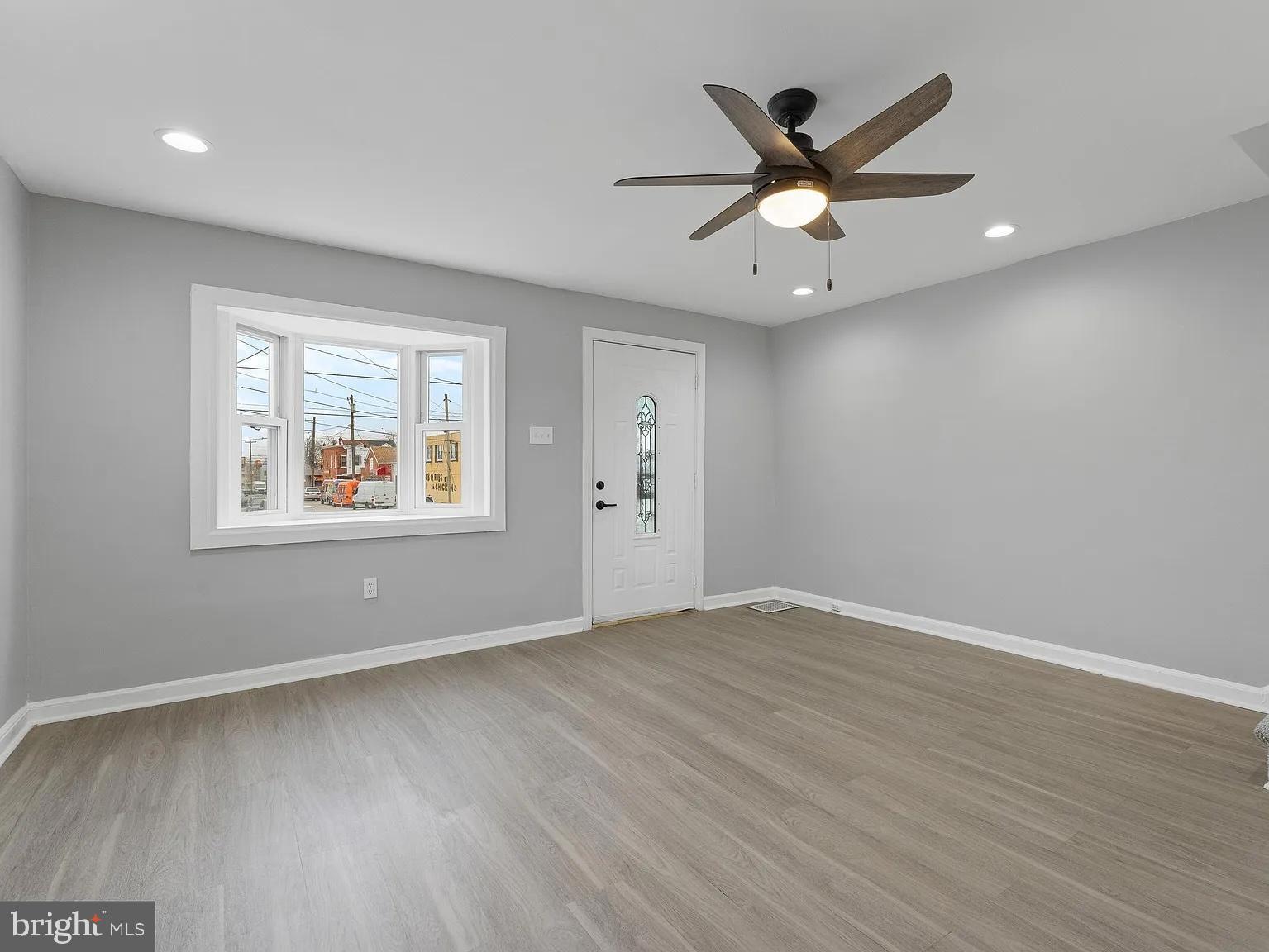 1006 Butler Street Chester, PA 19013 - Photo 13 of 31 an empty room with wooden floor ceiling fan and windows