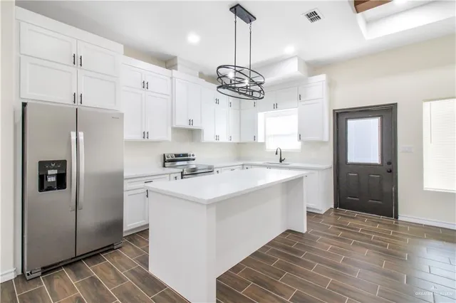 a kitchen with kitchen island granite countertop a sink appliances cabinets and counter space