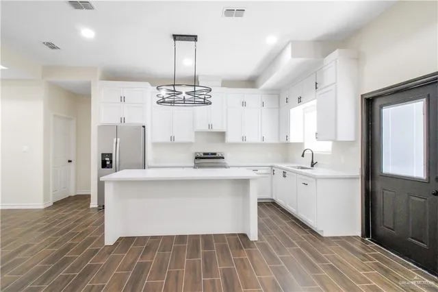 a large white kitchen with a sink and dishwasher a stove with wooden floor