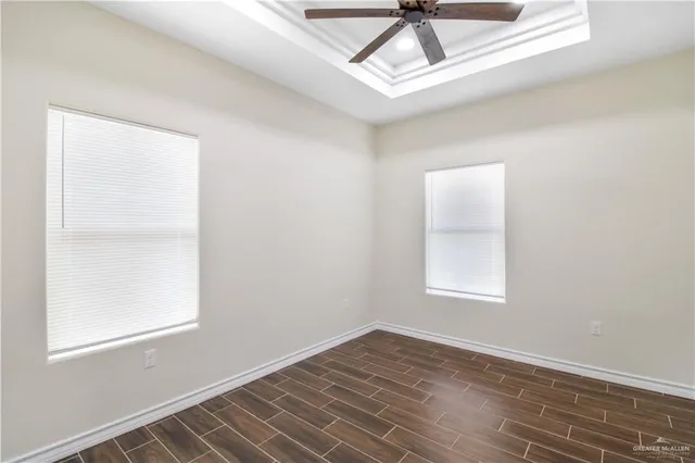 an empty room with wooden floor fan and windows