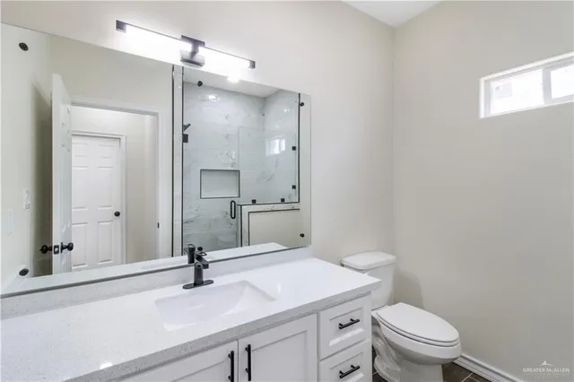 a bathroom with a sink a toilet a mirror and shower