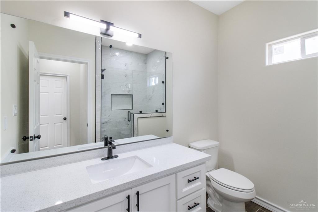 2126 Trinity Street Donna, TX 78537 - Photo 10 of 15 a bathroom with a sink a toilet a mirror and shower